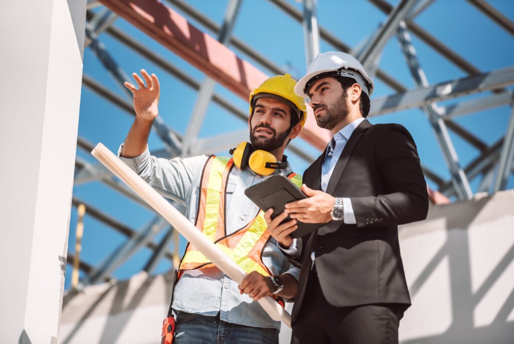 Civil engineer and construction worker manager holding digital tablet and blueprints , talking and planing about construction site.  Cooperation teamwork concept.